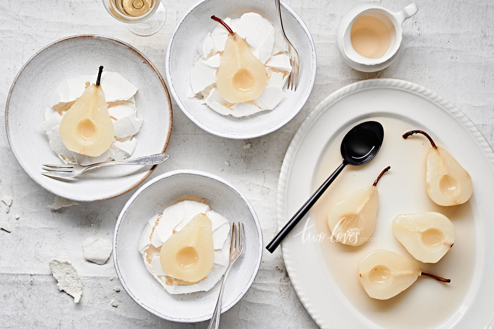 A flatlay of white wine poached pears. Served in bowls with meringue. There isn't any colour to this photo so it appears black and white even thought it's real food!