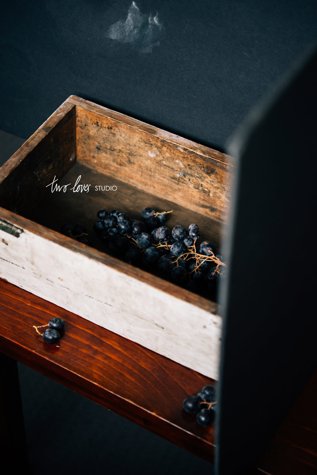 Behind the scenes shot of purple grapes in a wooden box and a reflector. 