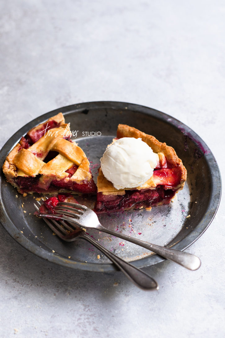 Two slices of plum pie with ice cream.