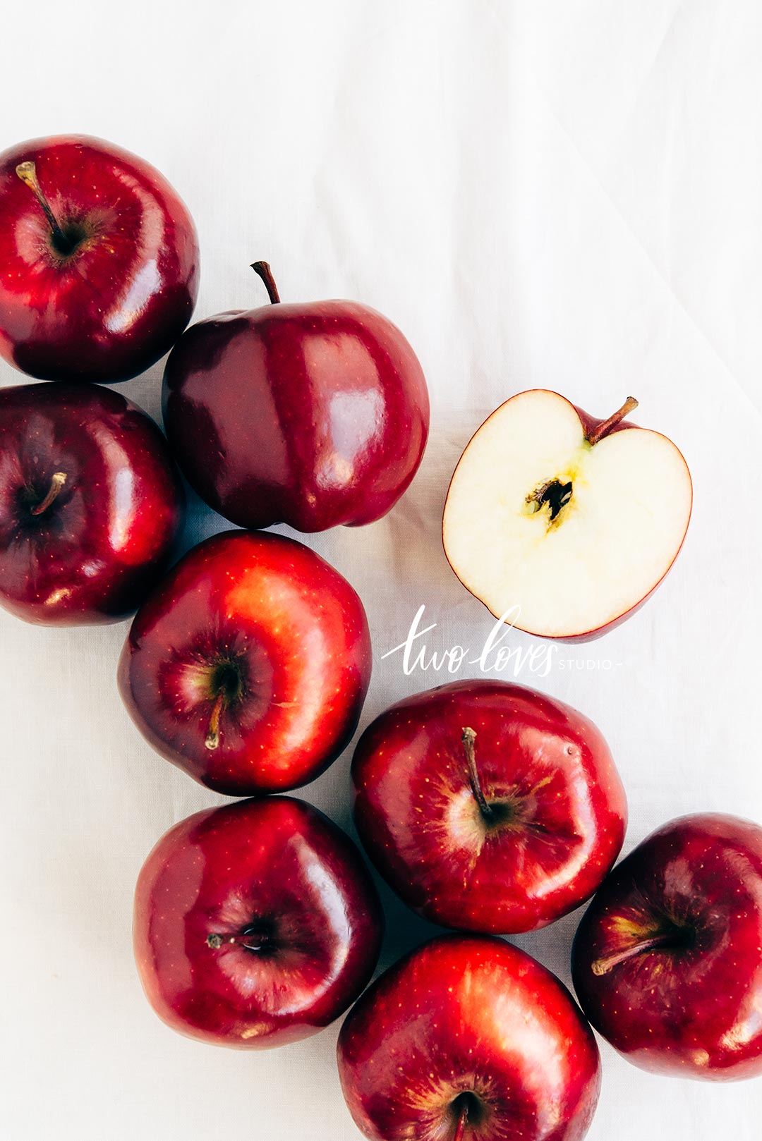 Shinny red apples with one cut in half. 