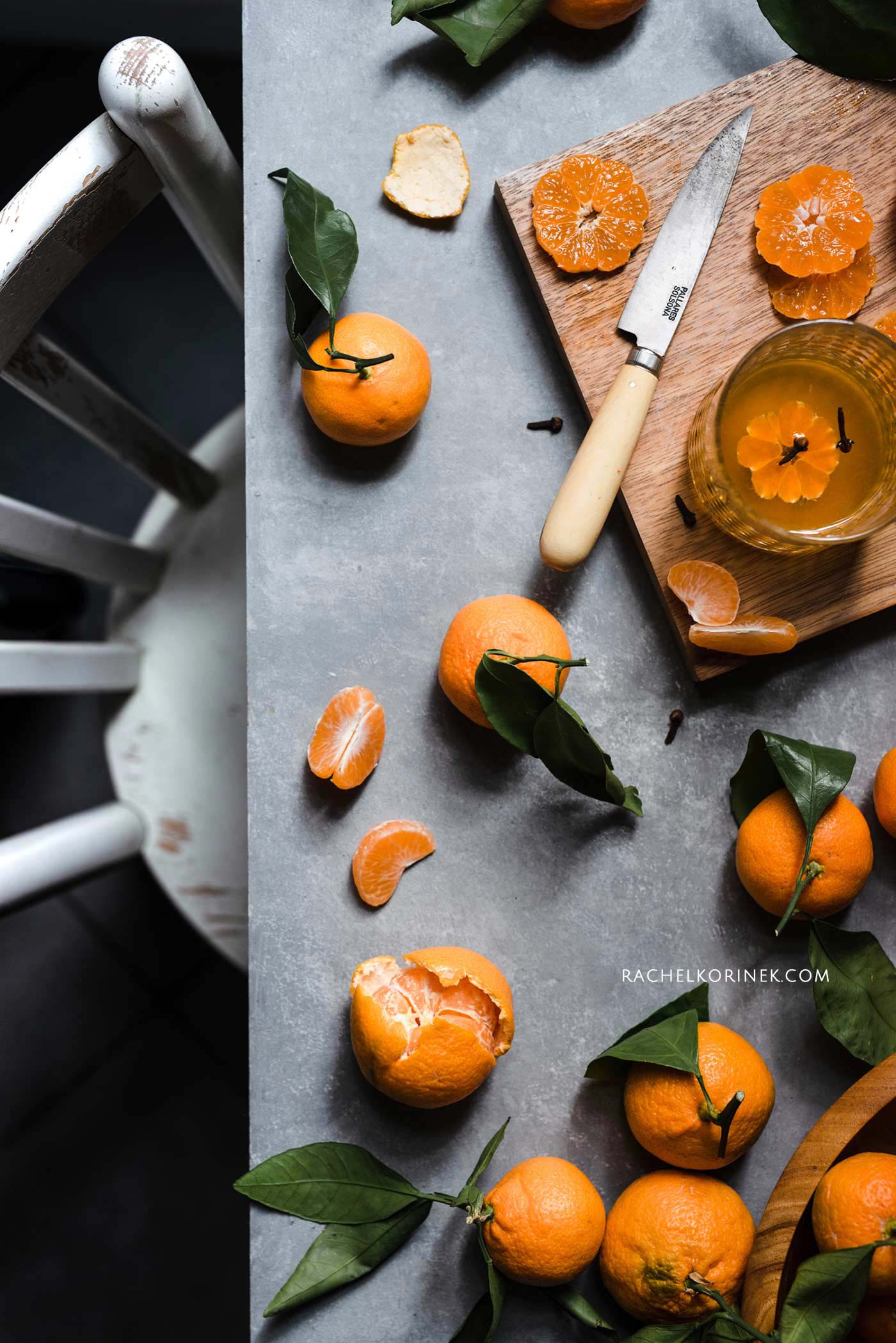 A table full of clementines, some cut up and a knife on the table. 