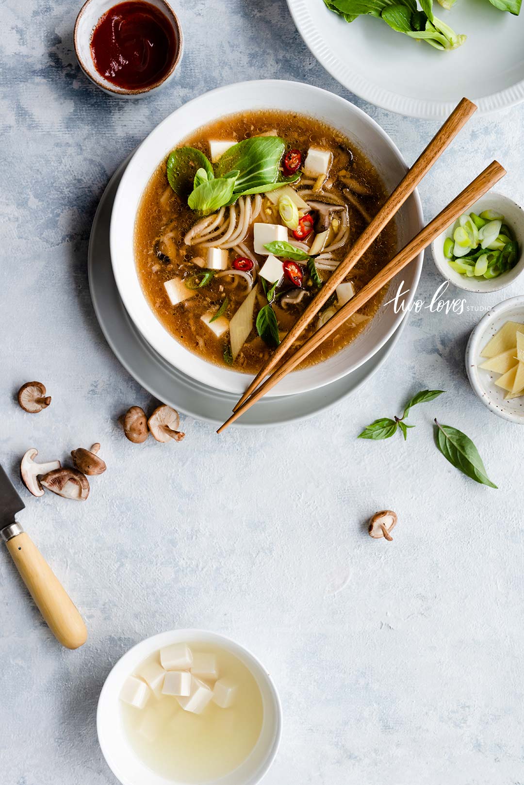 A white bowl with chopsticks and hot and sour soup.