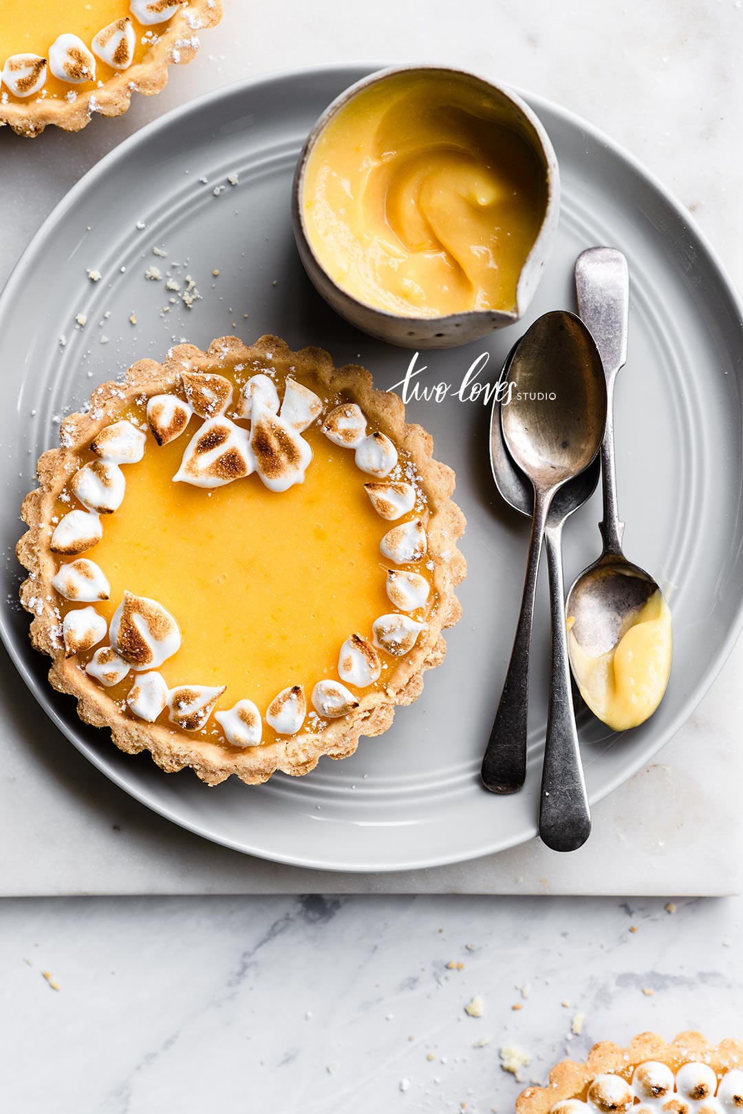 A green-grey plate with lemon tarts  and toasted edges. 