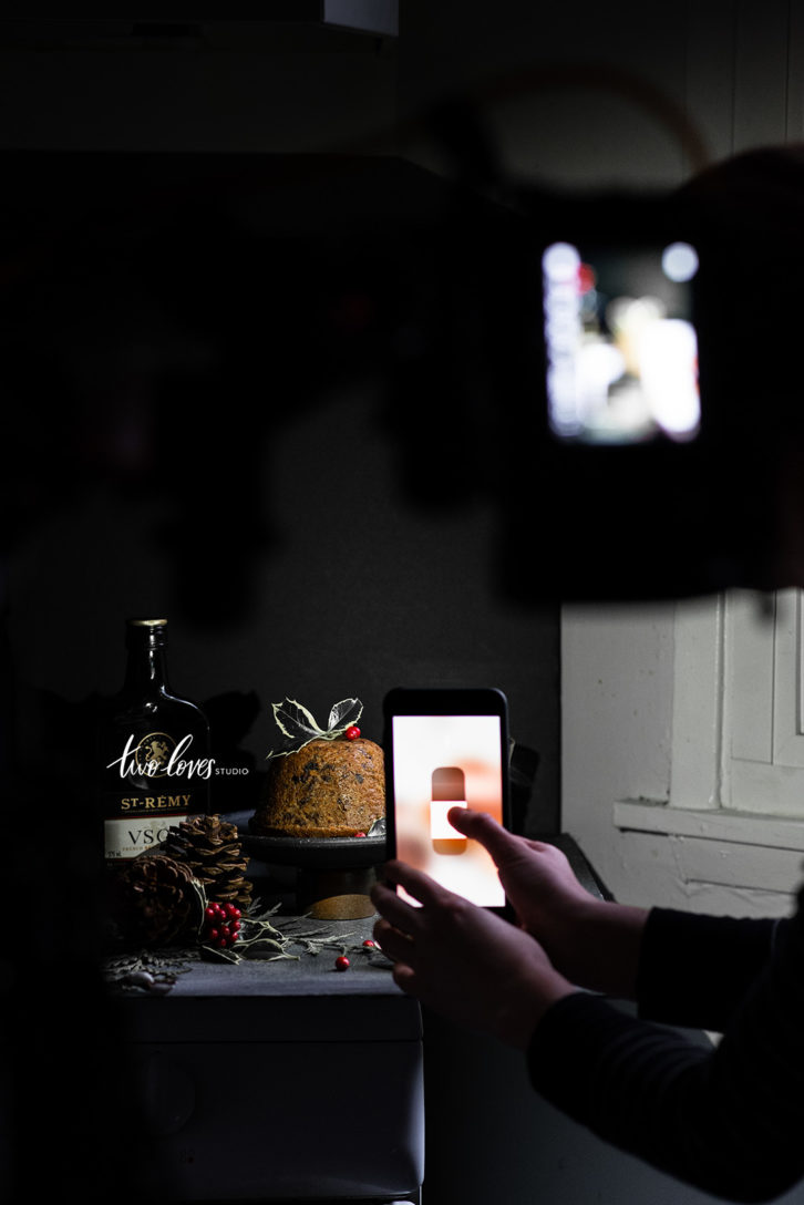 A Christmas pudding on a table while Rachel is taking a photo with the flash on her iPhone camera. 