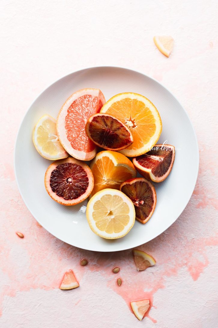 A white bowl of citrus fruit cut in half