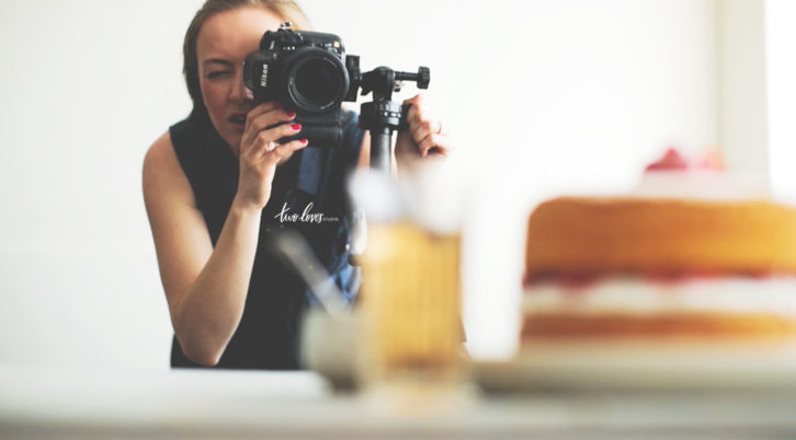 Rachel looking through a camera while taking a photo of a cake. 