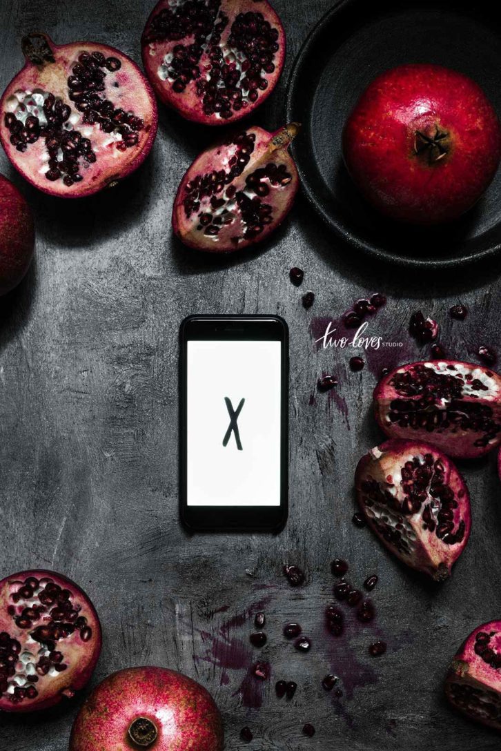 Flatlay photo showing a phone with a white background and a black X showing where to focus for the camera. 