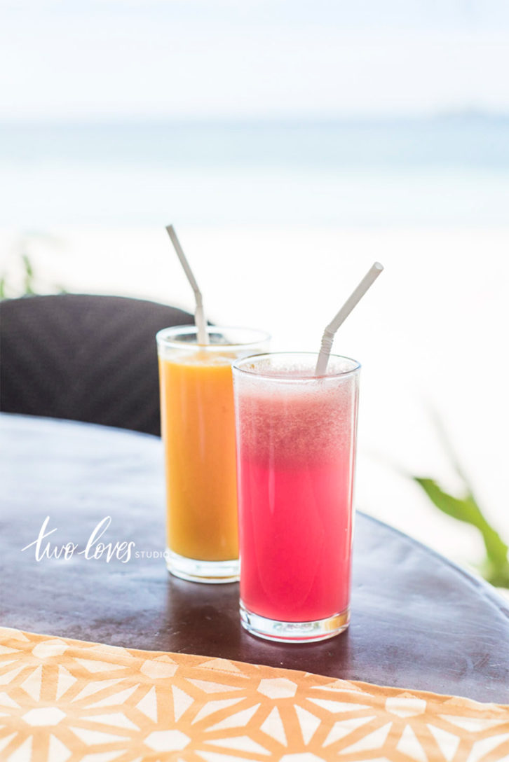 Two fruit drinks in glasses with a straw. 