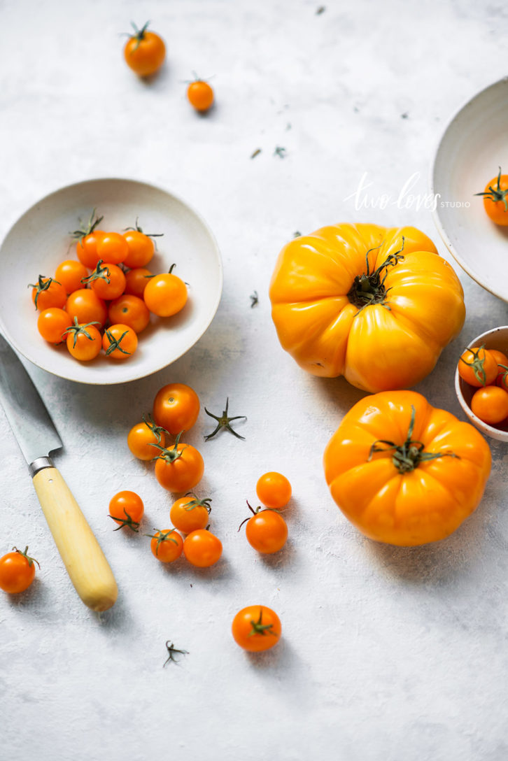 Two white bowls with orange small tomatoes in them. 