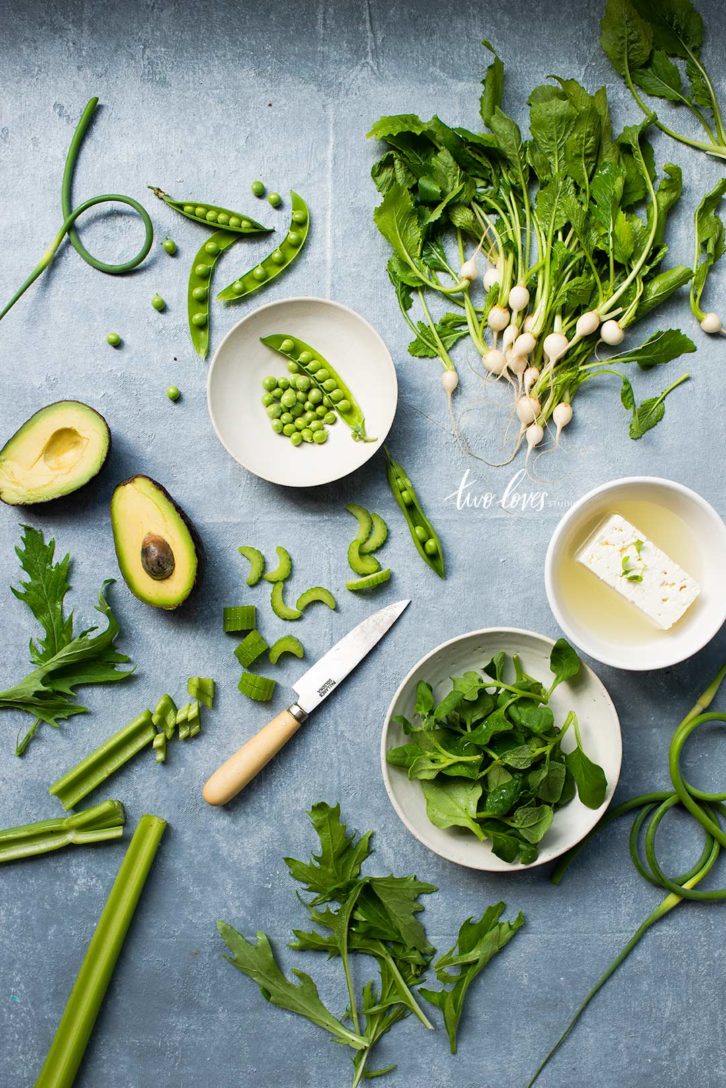 An assortment of green vegetables on a grey blue background.