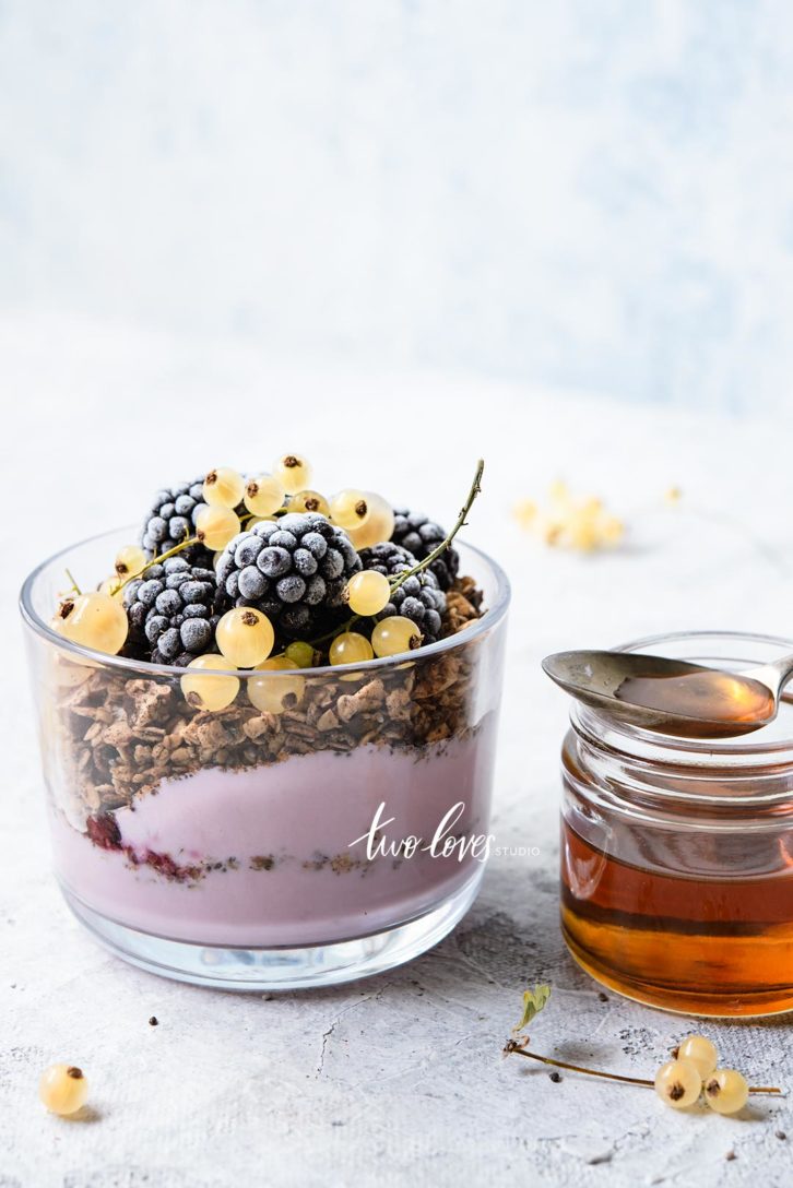 A jar of yogurt with granola and berries