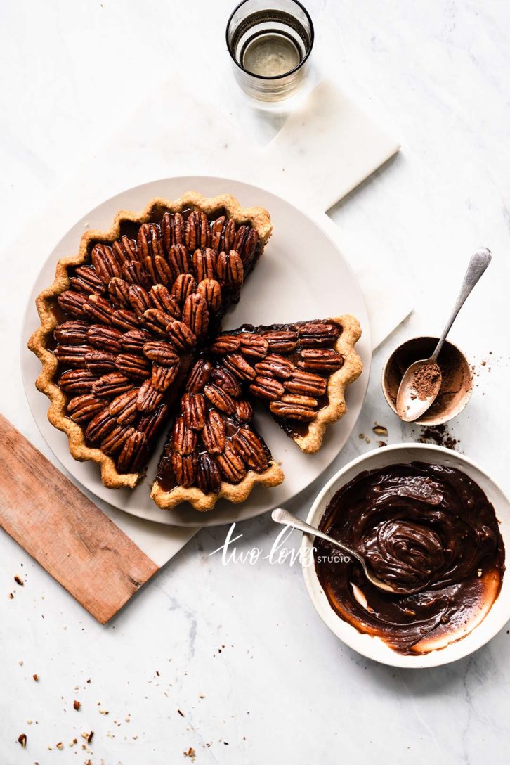 Pecan Pie cut up on a white plate.