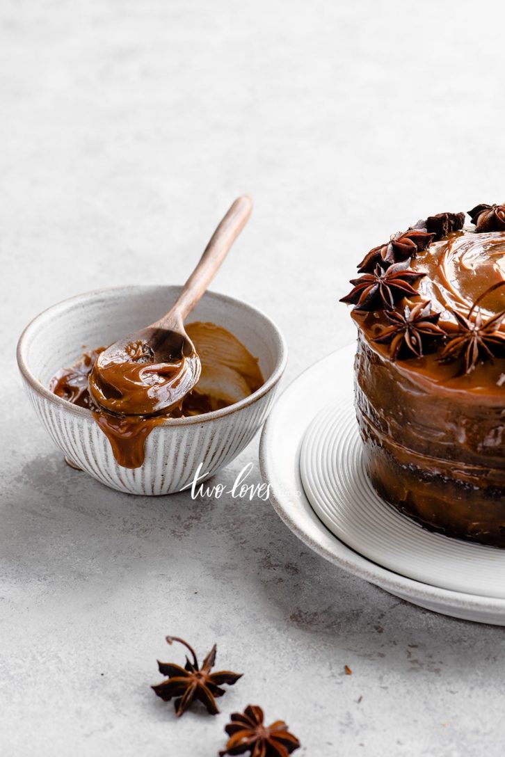 A caramel cake with a clove design on top in a ring. A side bowl with extra caramel sauce. 