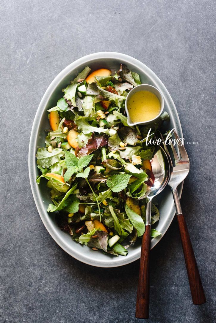 A plate of salad with a side of dressing.