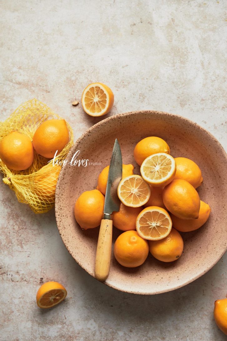 A bowl of lemons with some cut in half