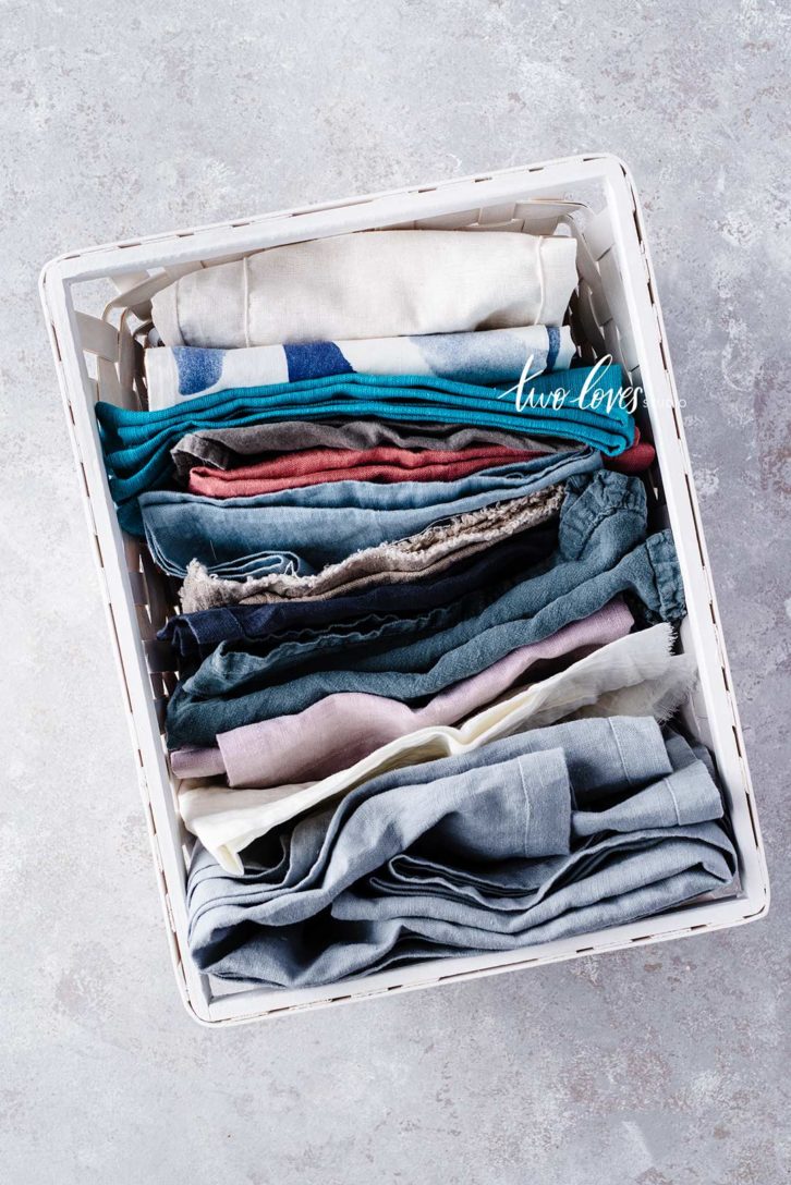 A basket of folded napkins of various colours