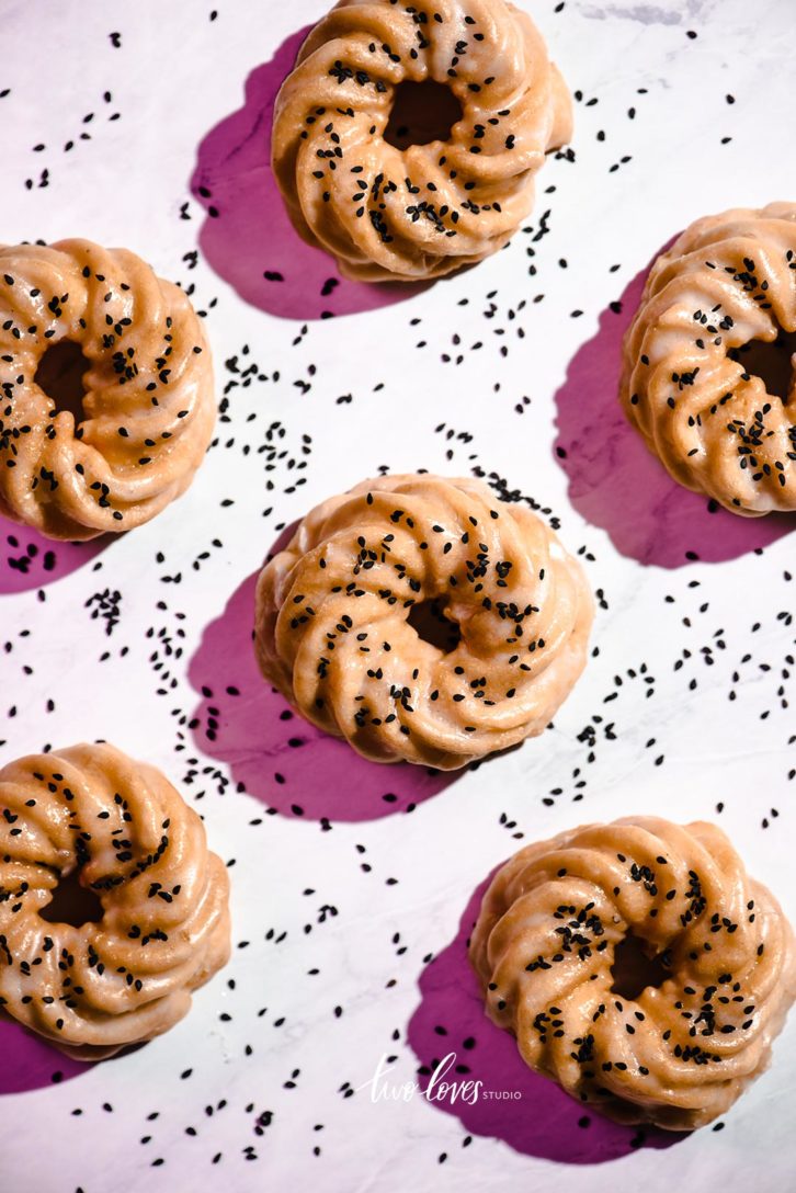Swirl Donuts arranged on a pink backdrop with black sesame seads.