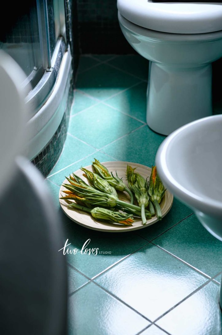 A plate of green vegetables in a bowl on the floor with green tiles.