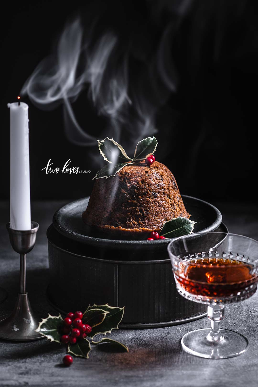 Christmas pudding food photography scene with candles and smoke.