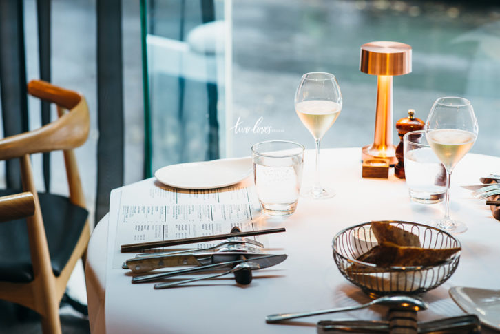 White table cloth, restaurant setting with wine glasses and a bread basket.