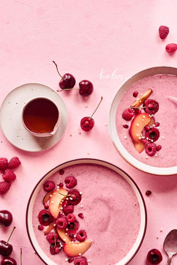 Pink smoothie bowl with fresh fruit. Raspberries and peaches. 