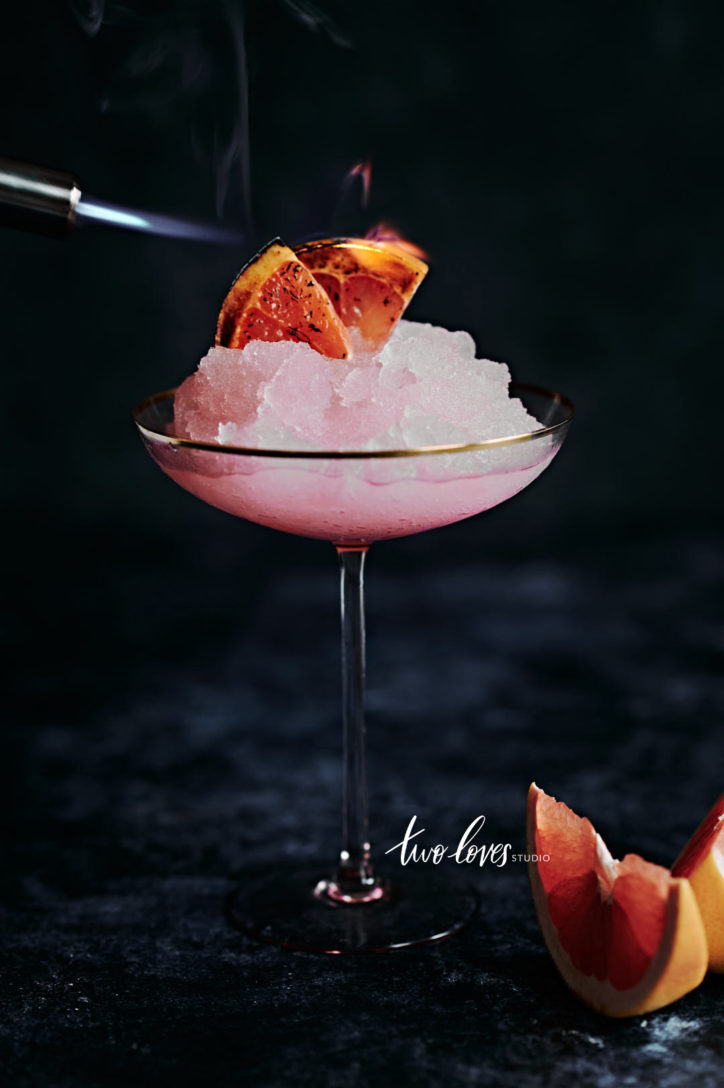 Pink icy cocktail with charred grapefruit slices.