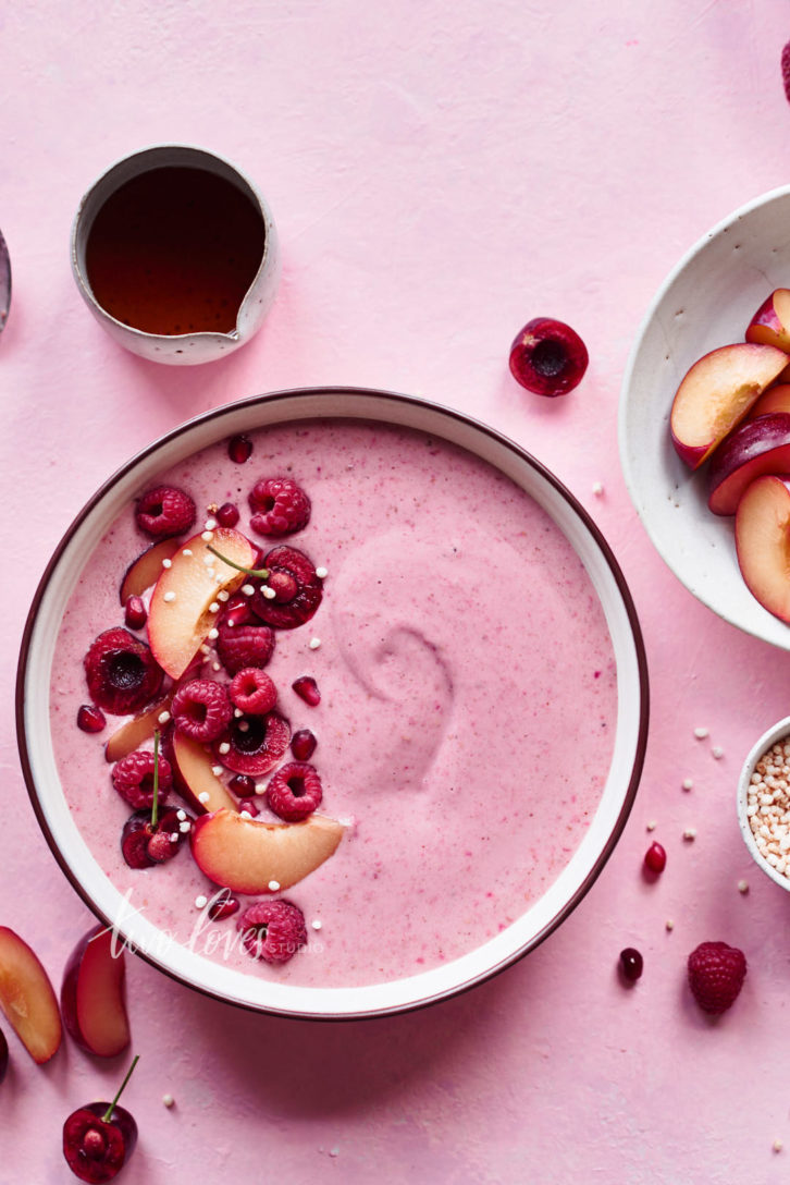 Pink berry smoothie bowl with berry and fruit garnish. White balance in this shot makes the shot cooler.