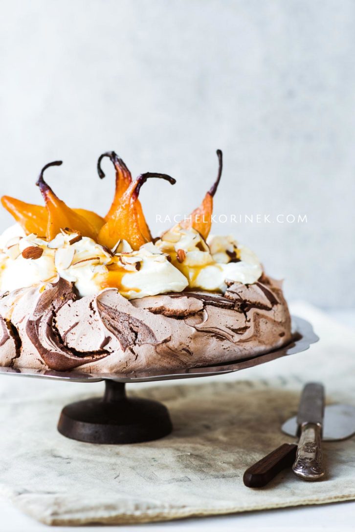 Chocolate Pavlova with poached pears and whipped cream on a cake stand.