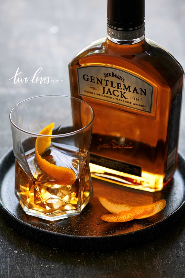 A single glass of gentleman Jack whiskey, slices of orange to decorate. 