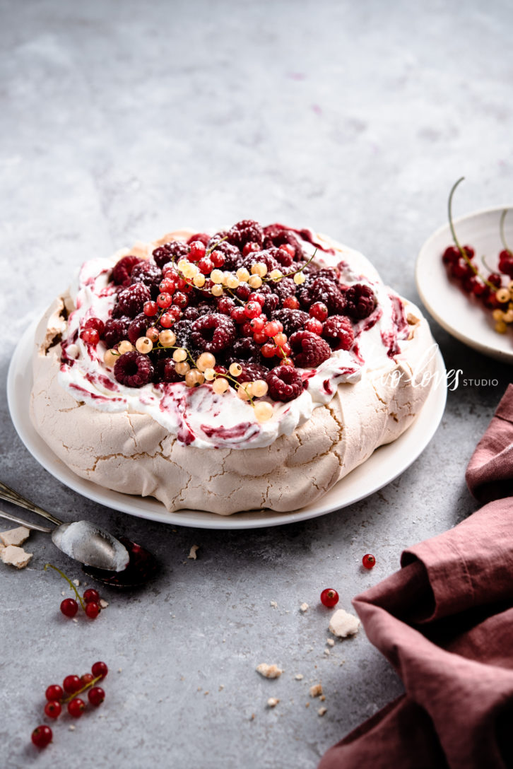 Traditional pavlova with smashed berries on top. 