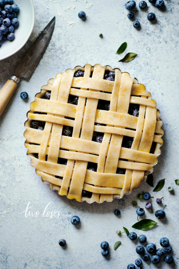 An uncooked blueberry pie with a double lattice work.