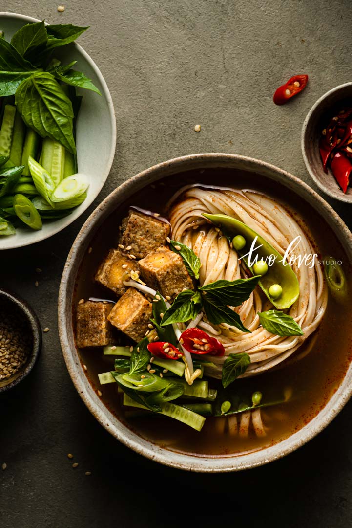 A bowl of Tom Yum Noodle soup with cubed tofu. Showing camera settings for food photography and depth of field.