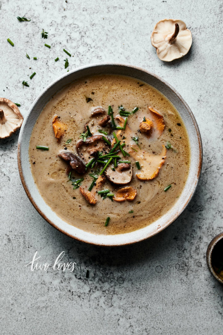 An overhead bowl of mushroom soup with a garnish of lightly fried shiitake and chantrelle mushrooms.