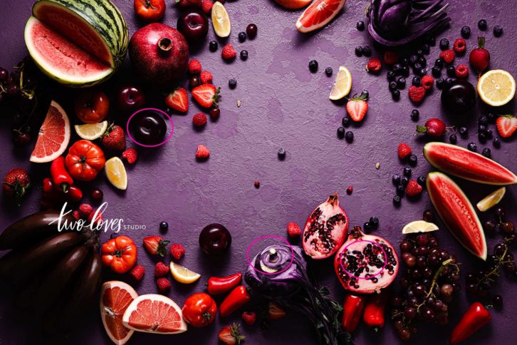 A flat lay of purple, red and yellow fruits on a purple background. Like watermelon, pomegranates, red bananas, strawberries and red grapes. Showing camera settings for food photography and over head flat lays