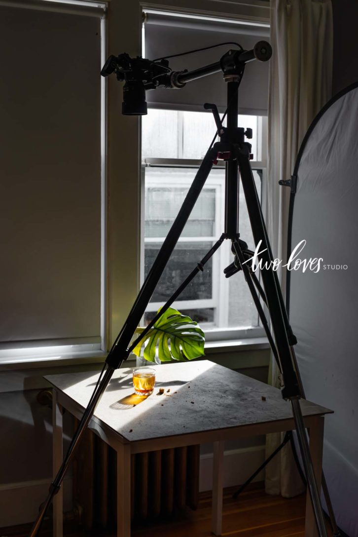 Behind the scenes of a hard light whiskey photo with creative natural lighting for food photography.