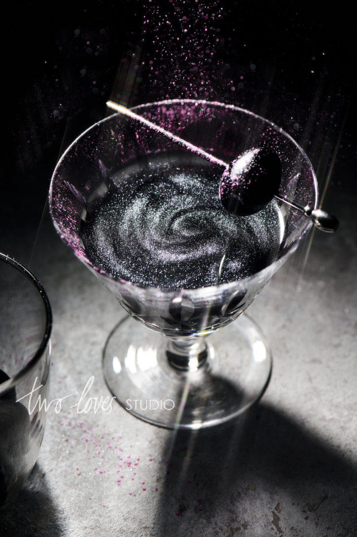 A black cocktail - black magic martini with edible pearl dust sprinkles. Showing how to use camera settings to freeze motion.