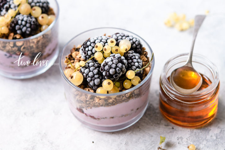 Bowls of yogurt parfait with a side of honey. 