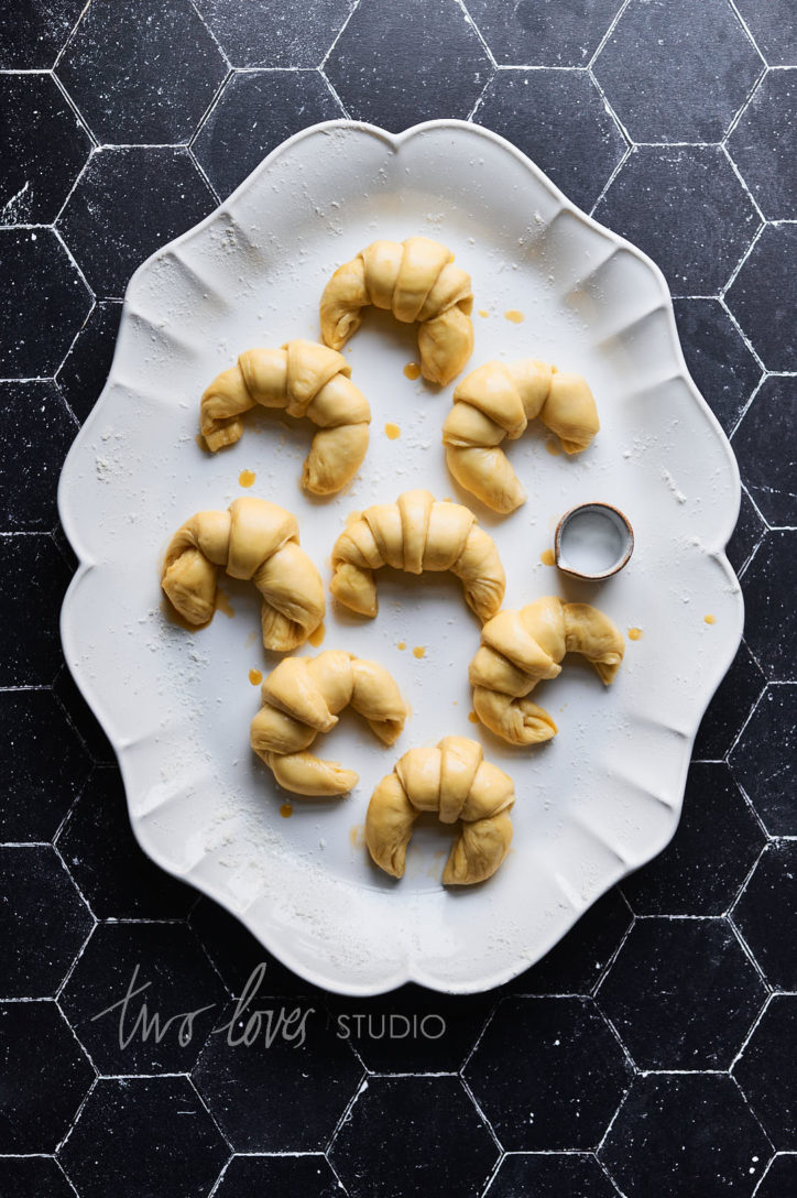 Black background with a white plate and mini croissants and a side jug. 