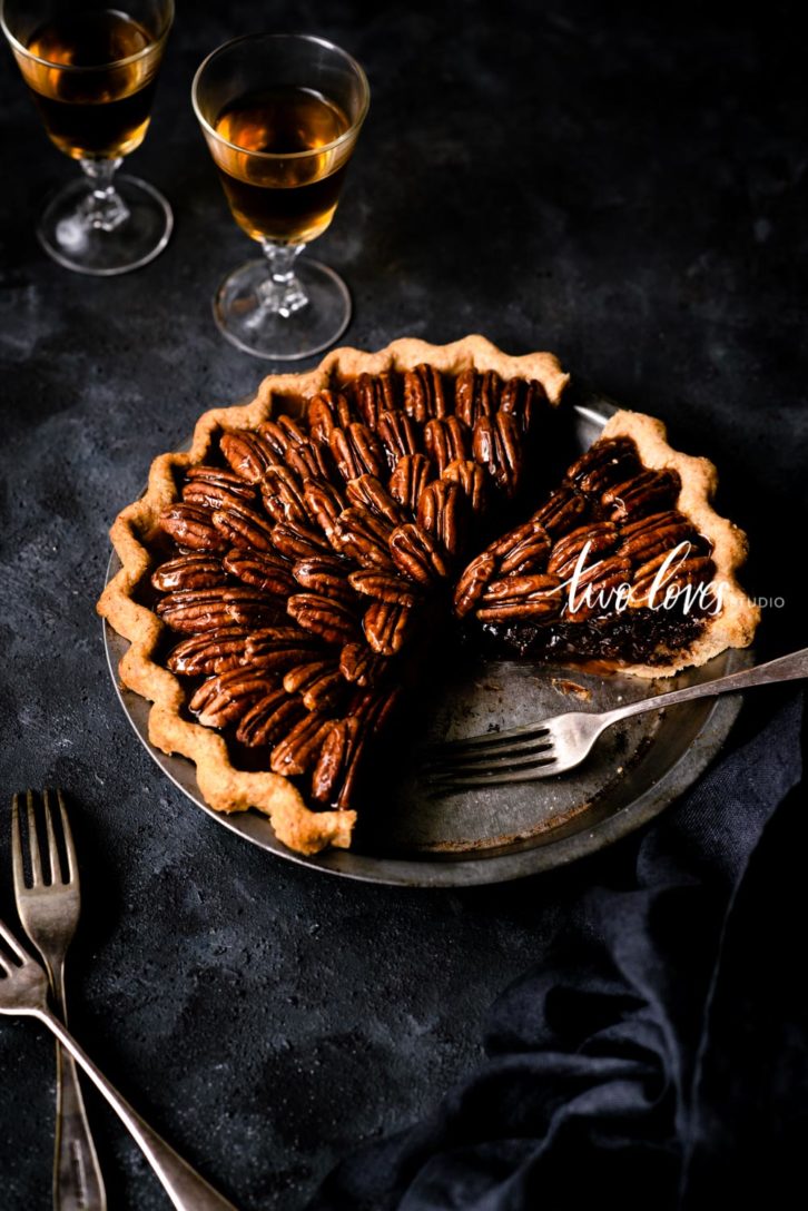 Dark blue background with a Pecan pie sliced in a cake tin. Shot with a 85mm 1.8 lens. Example of the 45 degree food shot.