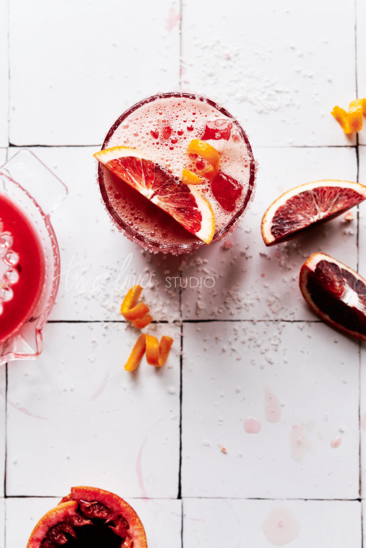 White Moroccan Tile Backdrop with a glass of blood orange margarita and slices of blood oranges.  