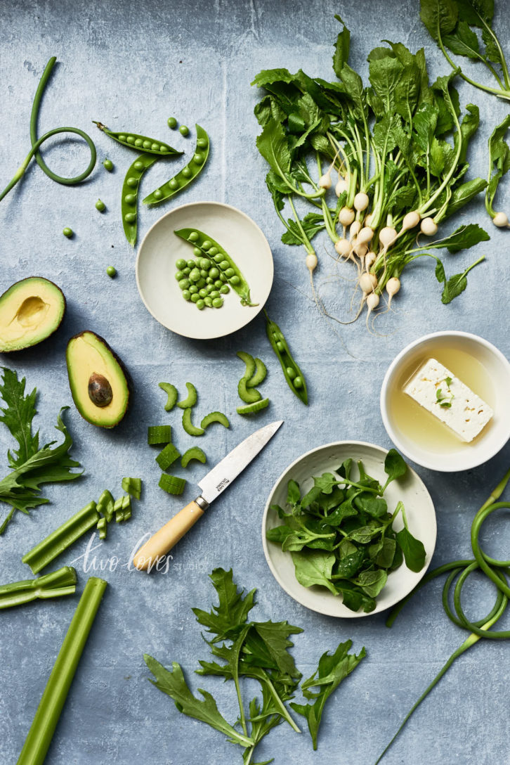 Flat lay shot of green vegetables on a blue background.