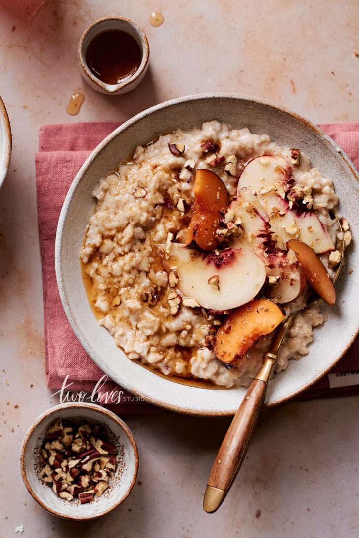 Fresh bowl of oatmeal with nectarines, plums and maple syrup.