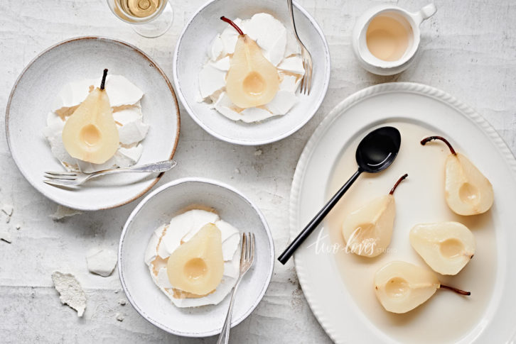 Poached pears cut in half on top of a meringue. 