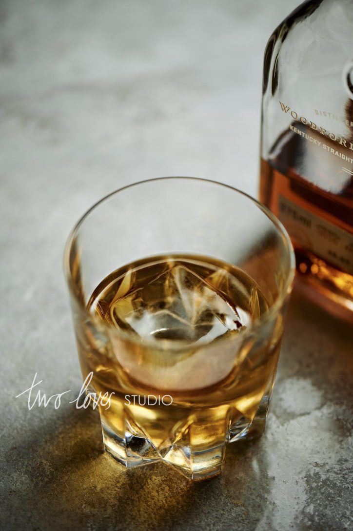 Marble background with Woodfood Reserve Whiskey bottle in a rocks glass. Taken with a 105mm macro lense at a 45 degree angle.