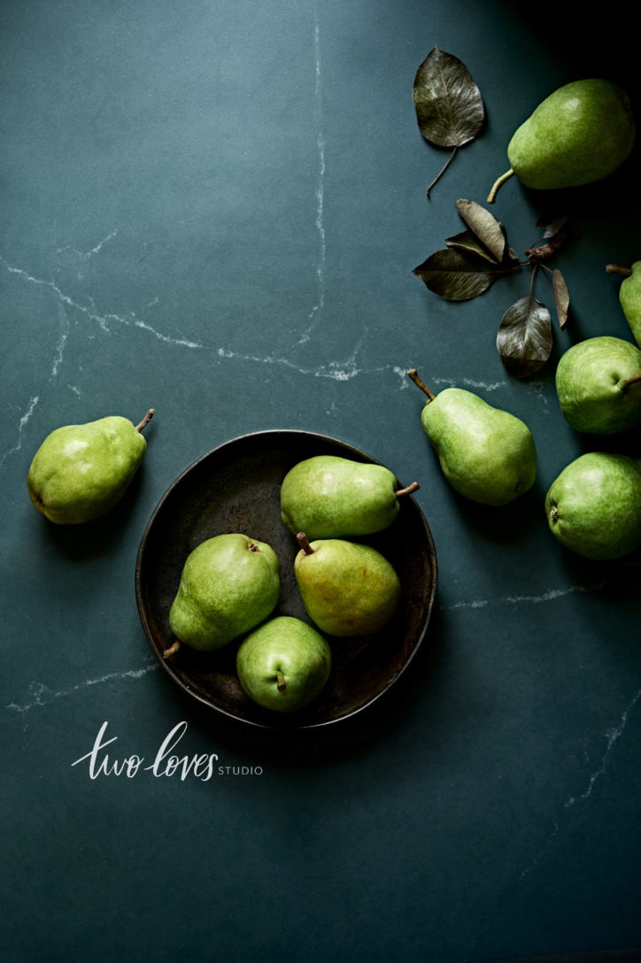 Overhead shot of green pears in a black bowl.