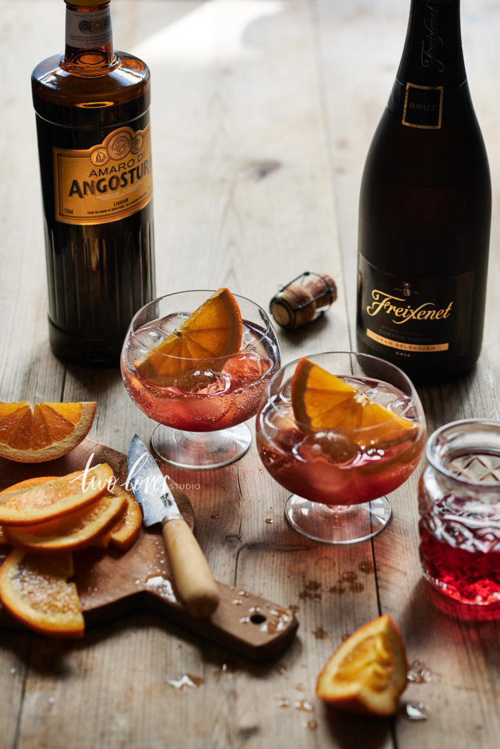 Hibiscus Fizz in two small cocktail glasses with slices of orange.