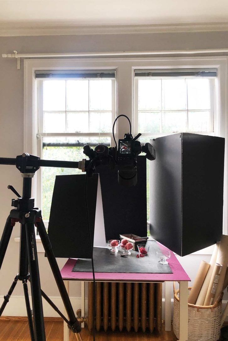 behind the scenes lighting setup for a frozen sorbet shoot. With a camera on a tripod and black foam boards to block light.