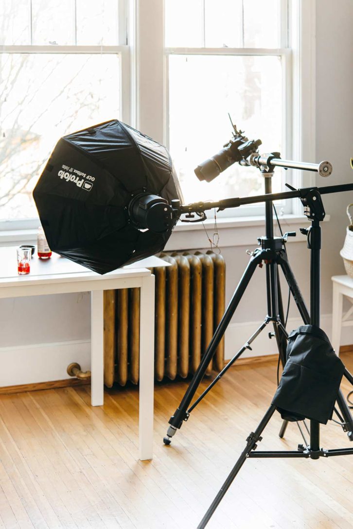 behind the scenes in a food photography studio of a camera on a tripod and artificial light on a lighting stand.