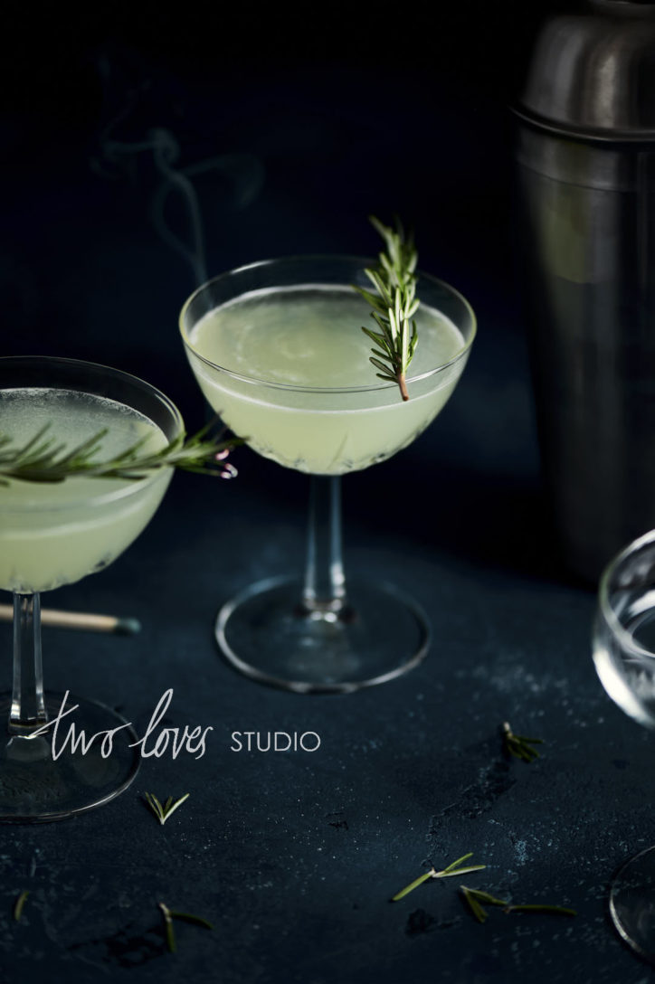 Two light green cocktail glasses with Rosemary sprigs as garnish. 