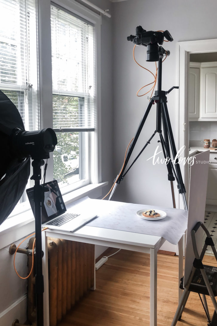 Equipment for food photographers wide shot setup of a tripod overhead shot with a single plate on a marble background.